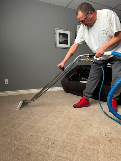 Technician extracting carpet next to a sofa in a finished basement