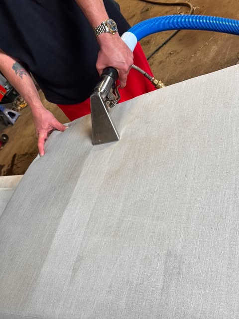 Upholstery cleaning tool being used on a light grey fabric cushion